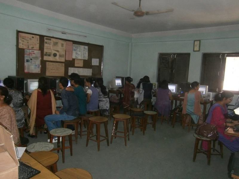 Rows of teachers seated at computers in a large training room