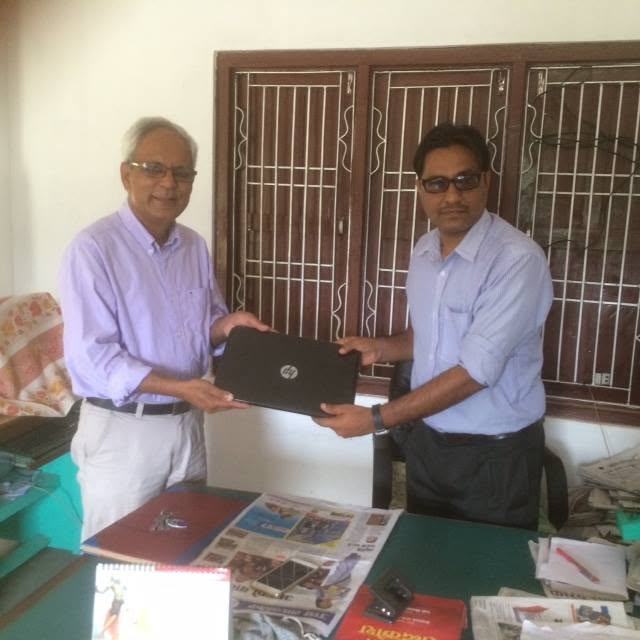 A FEDUC representative hands a laptop to a school official